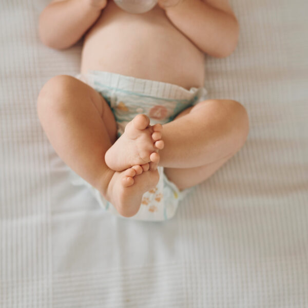 Beba leži s podignutim i prekriženim nogama, zatvor