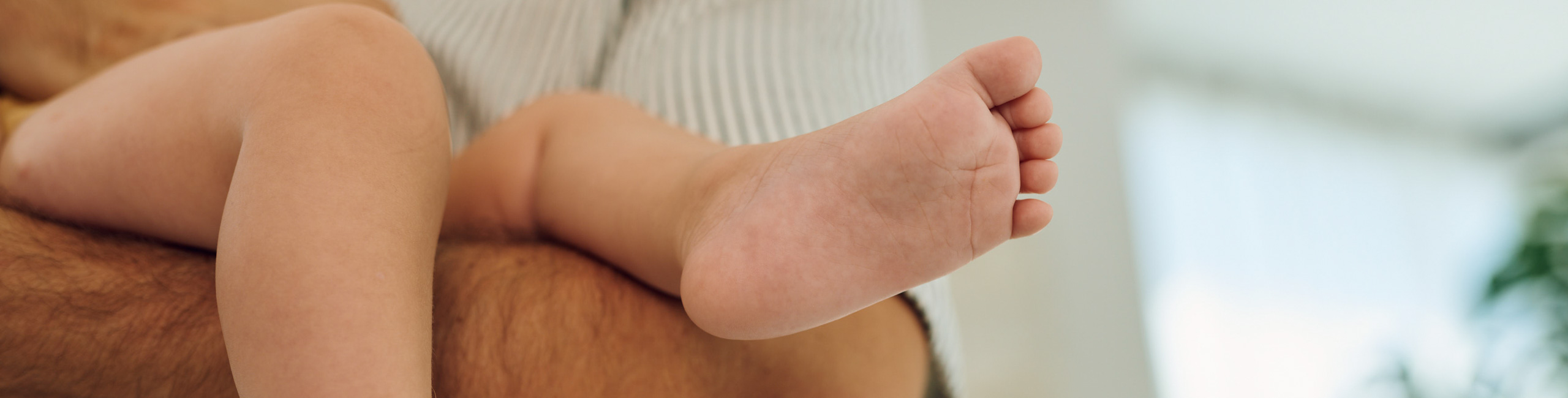 Bebine noge u naručju roditelja.