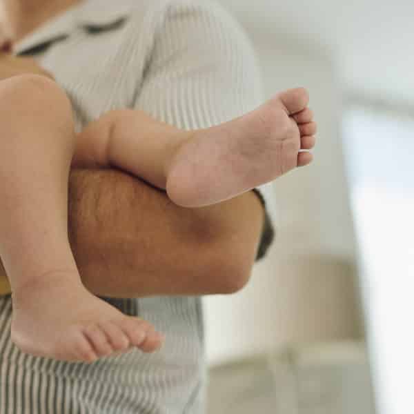 Bebine noge u naručju roditelja.