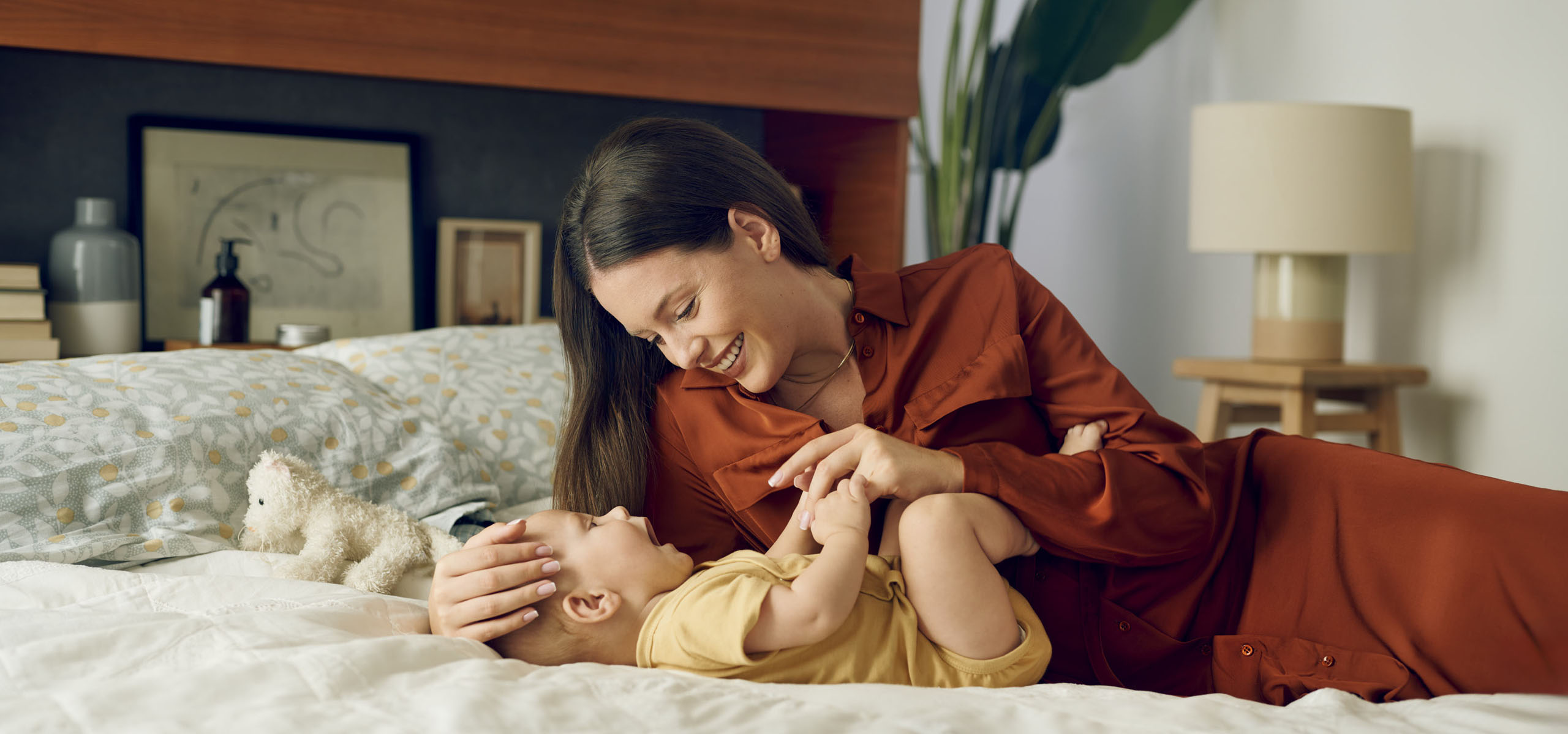 Majka se igra sa svojom bebom na krevetu.