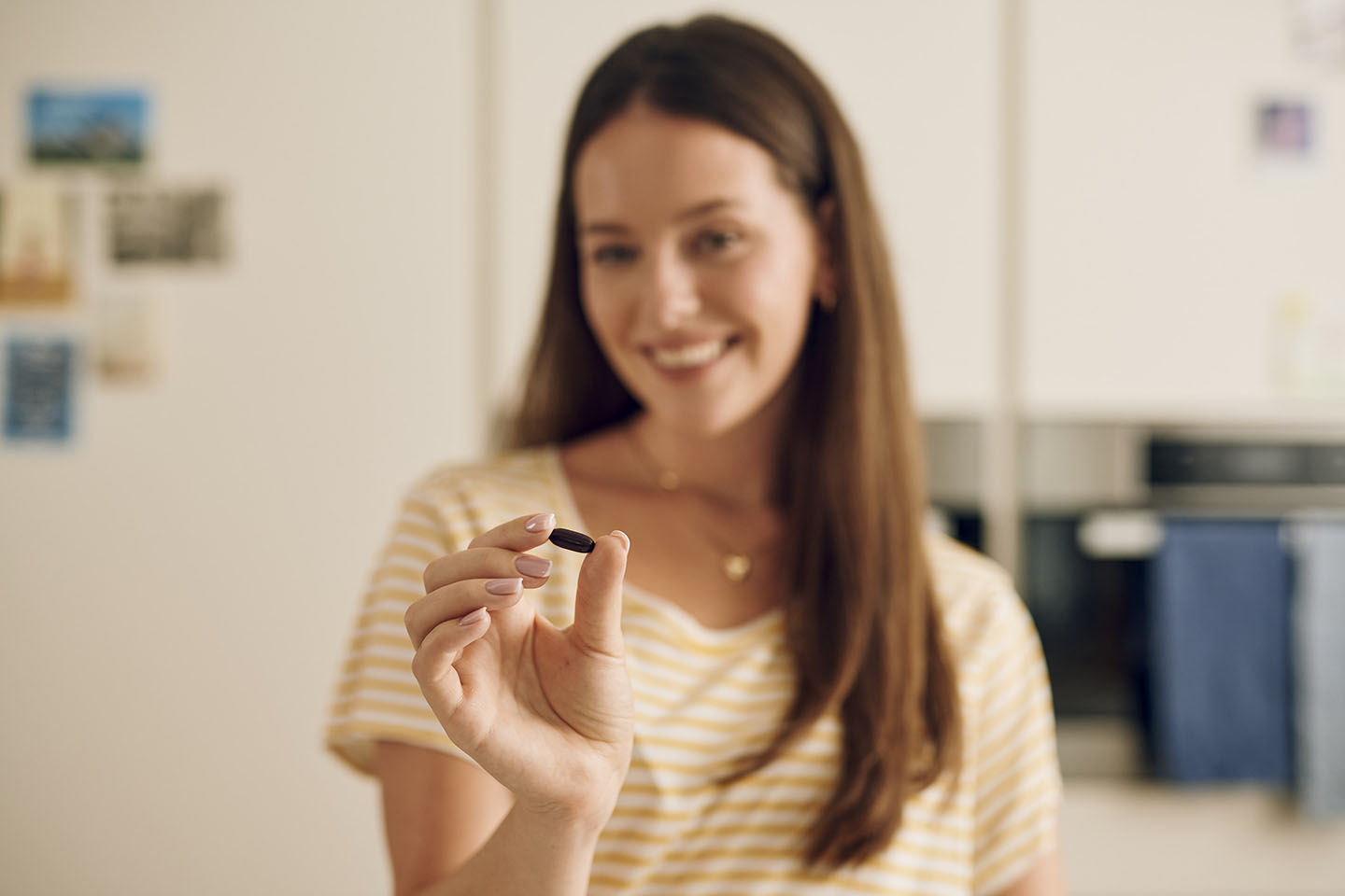 Žena drži prenatalnu kapsulu Novalac i priprema se za gutanje.