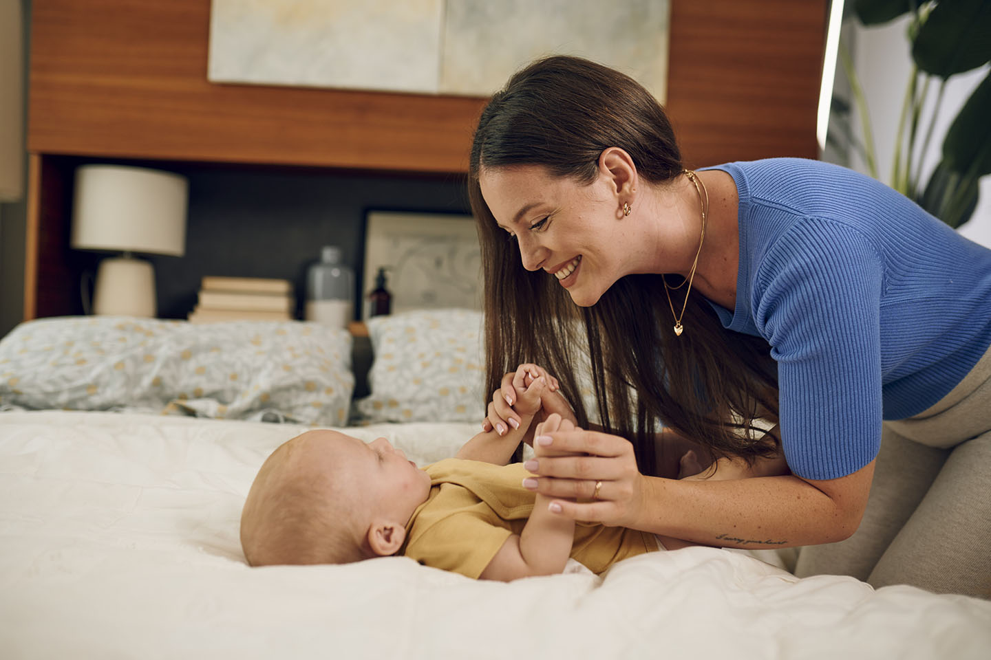 Majka se igra sa svojom bebom na krevetu.