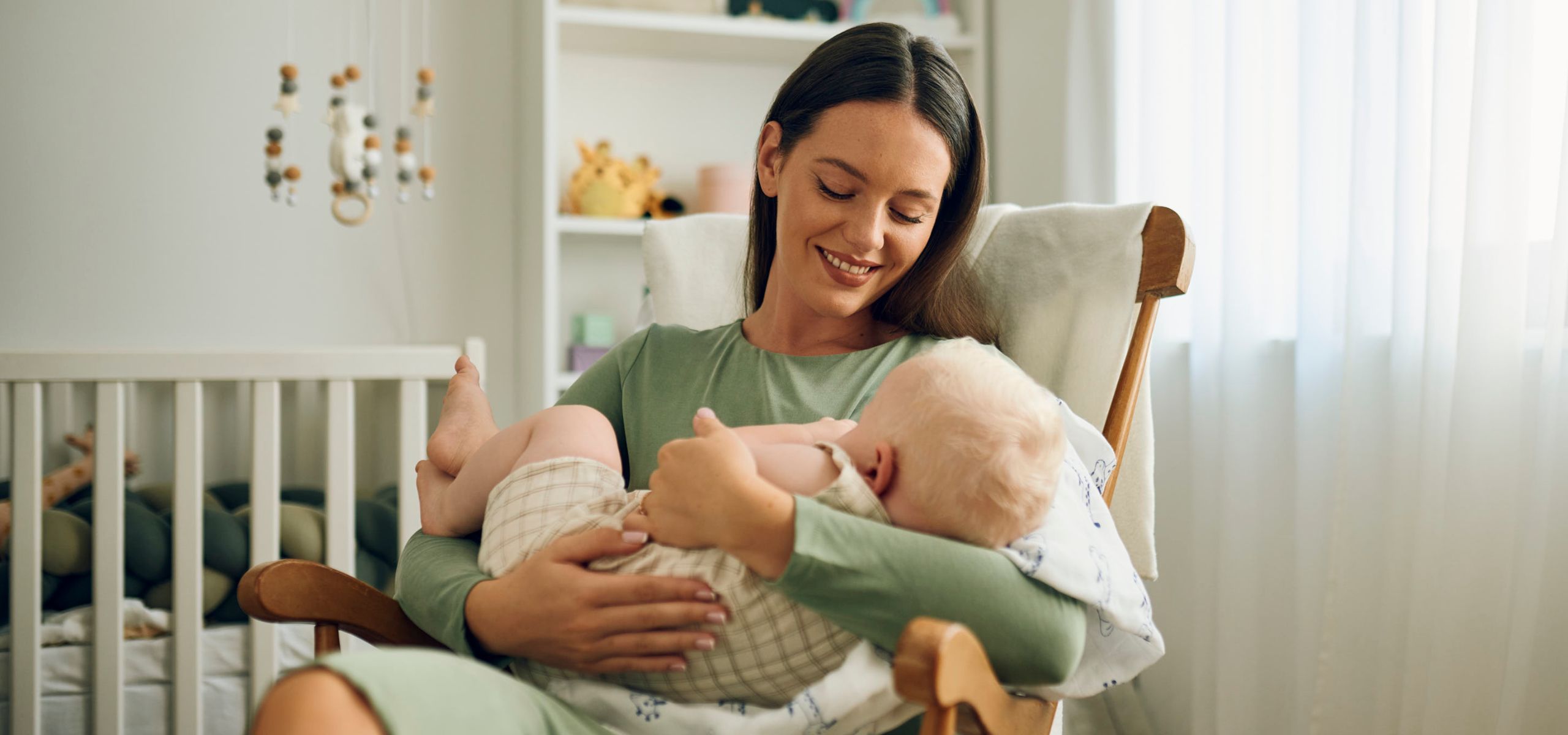 Majka drži bebu u naručju, priprema se za dojenje, nakon poroda.