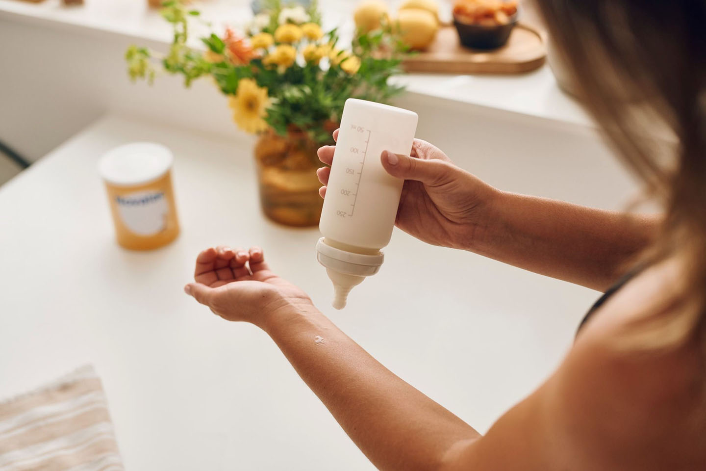 Mama priprema bočicu mlijeka u kuhinji - podrška za alergiju na proteine kravljeg mlijeka.