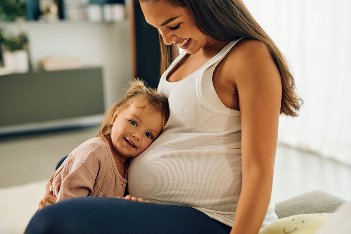 Djevojčica grli trbuh svoje trudne majke