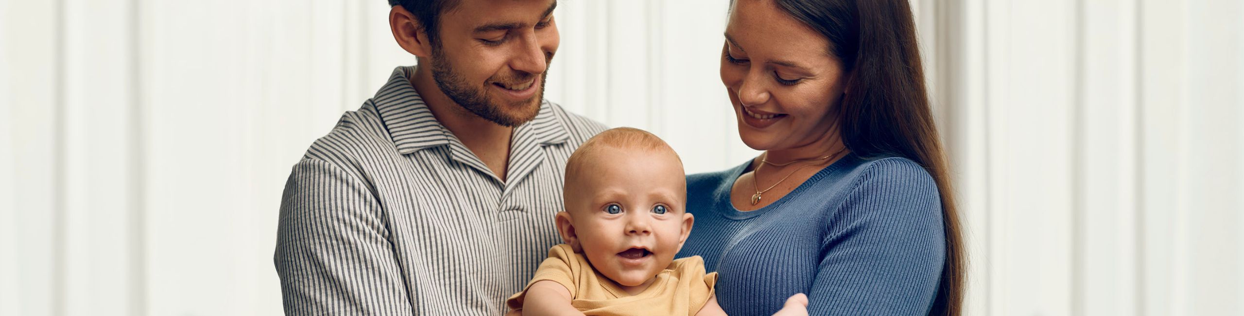 mama in oče držita v naročju dojenčka, srečna družina